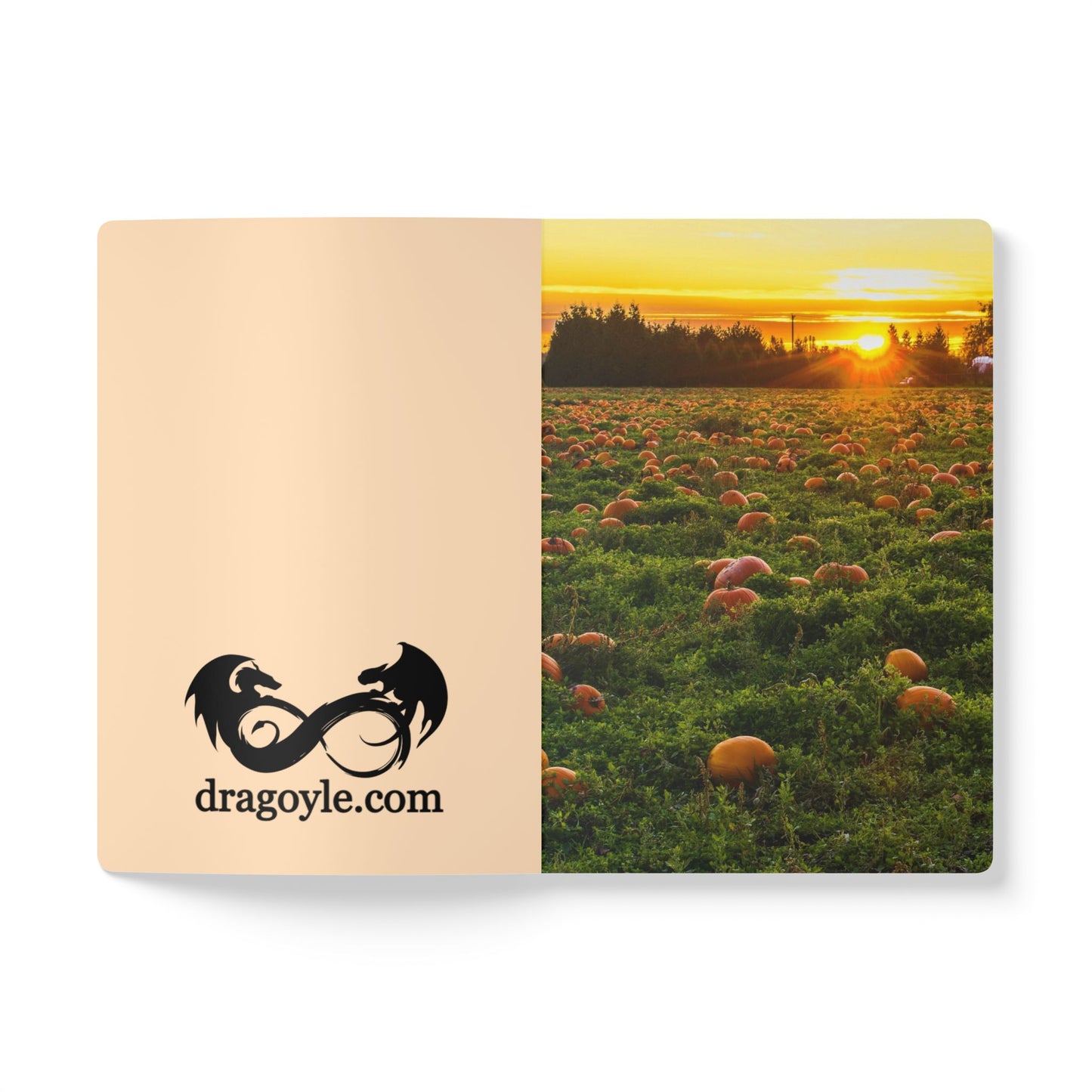 Notebook with a dragon design and 'dragoyle.com' text on the cover, featuring an image of a pumpkin patch at sunset.