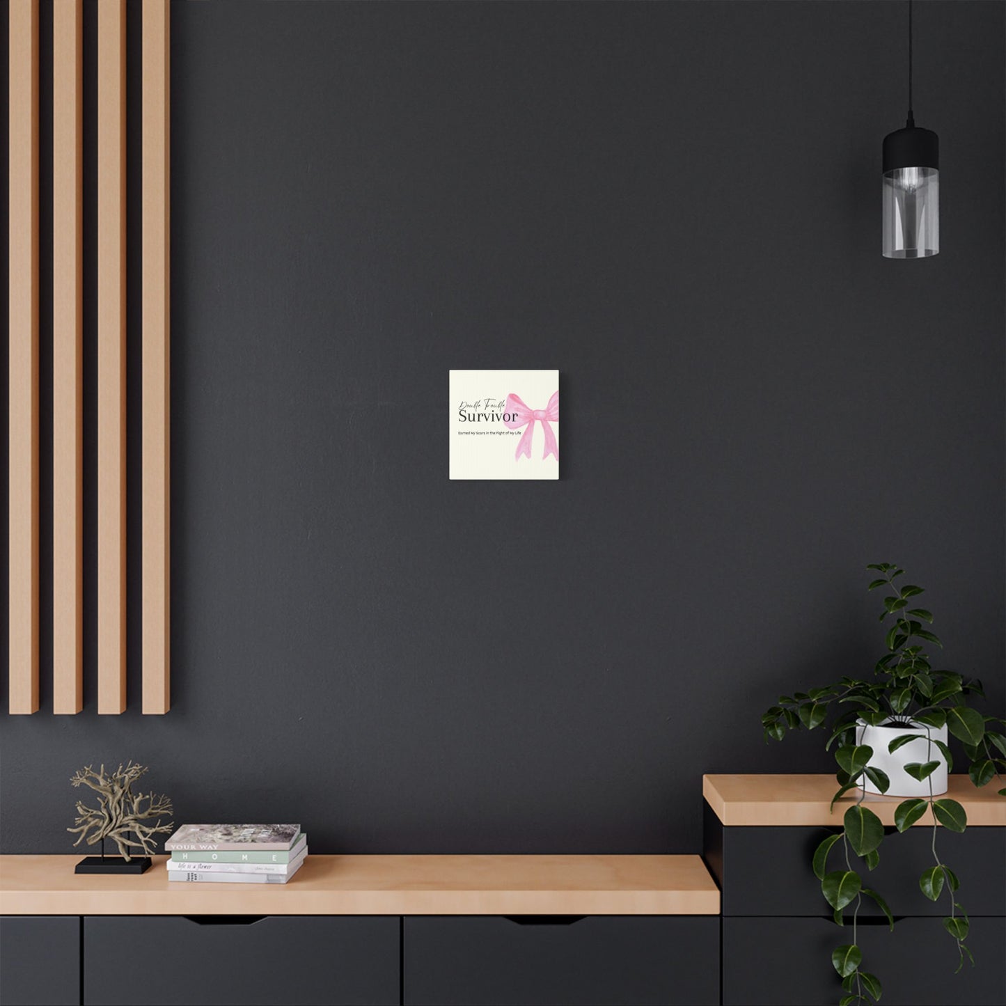Poster of a pink ribbon with text on a black wall above a wooden shelf.