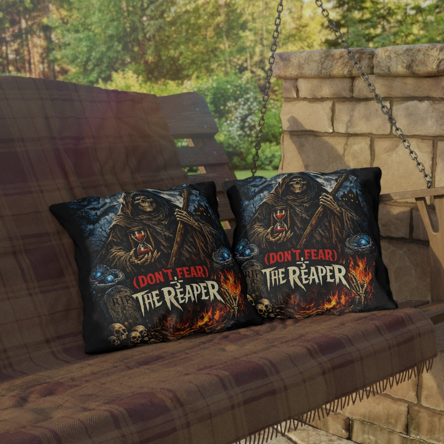 Two decorative throw pillows with a dark gothic graphic of a hooded figure and the text '(I DON'T FEAR) THE REAPER' in red and white, placed on a brown plaid porch swing in front of a stone wall.