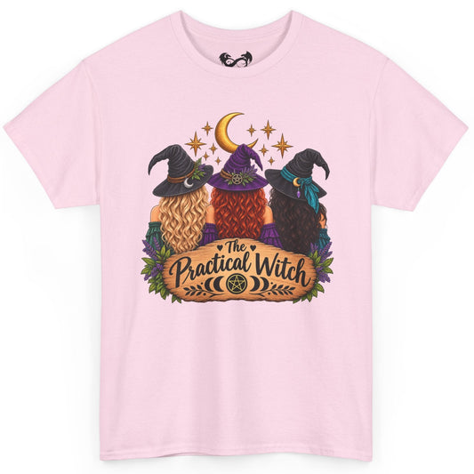 A light pink short-sleeve crewneck t-shirt featuring a colorful graphic of three witches in pointed hats under a crescent moon and stars, with a banner reading 'The Practical Witch'.