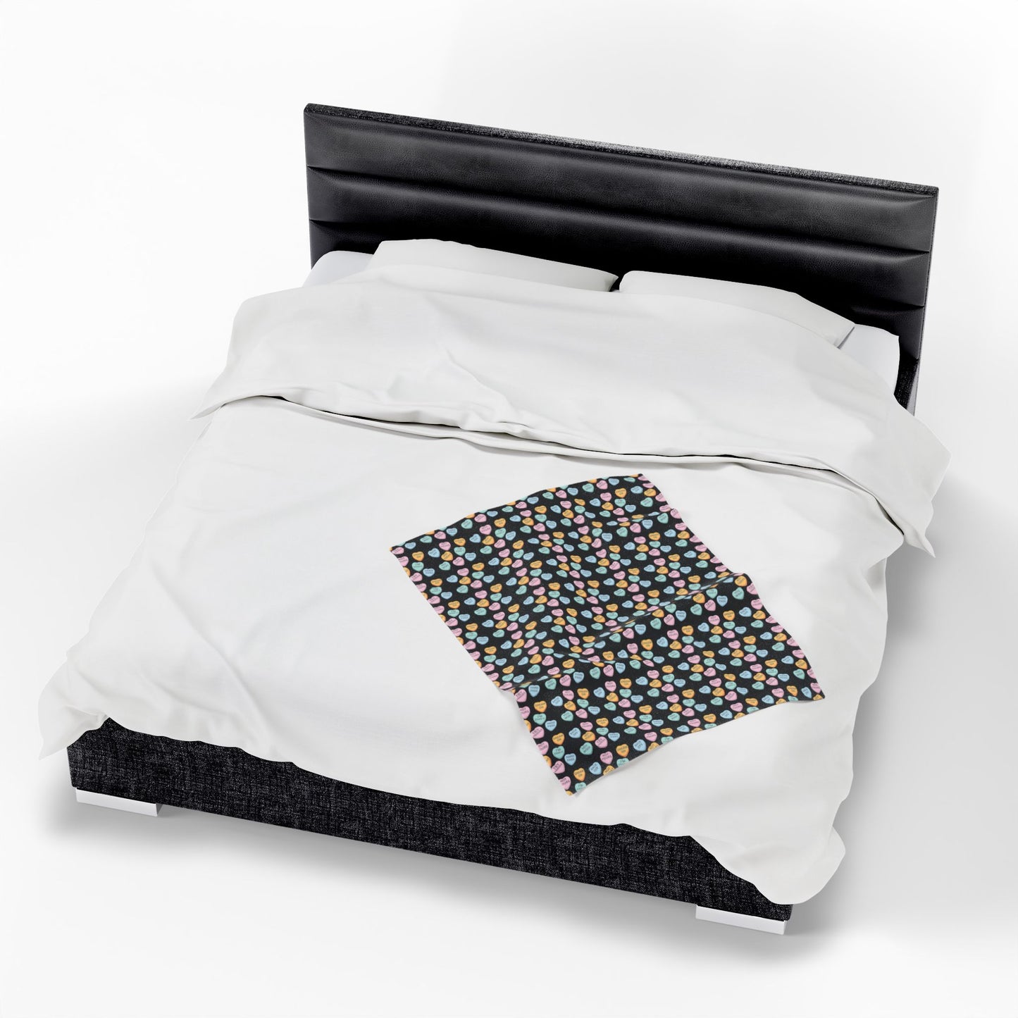 White comforter on a bed with a black headboard and a patterned blanket.