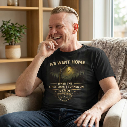 Man sitting on a couch wearing a black t-shirt with a graphic design and text.