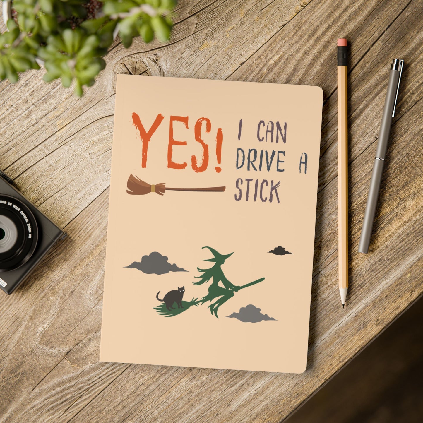 Notebook with a humorous design on a wooden surface with a pencil and pen.