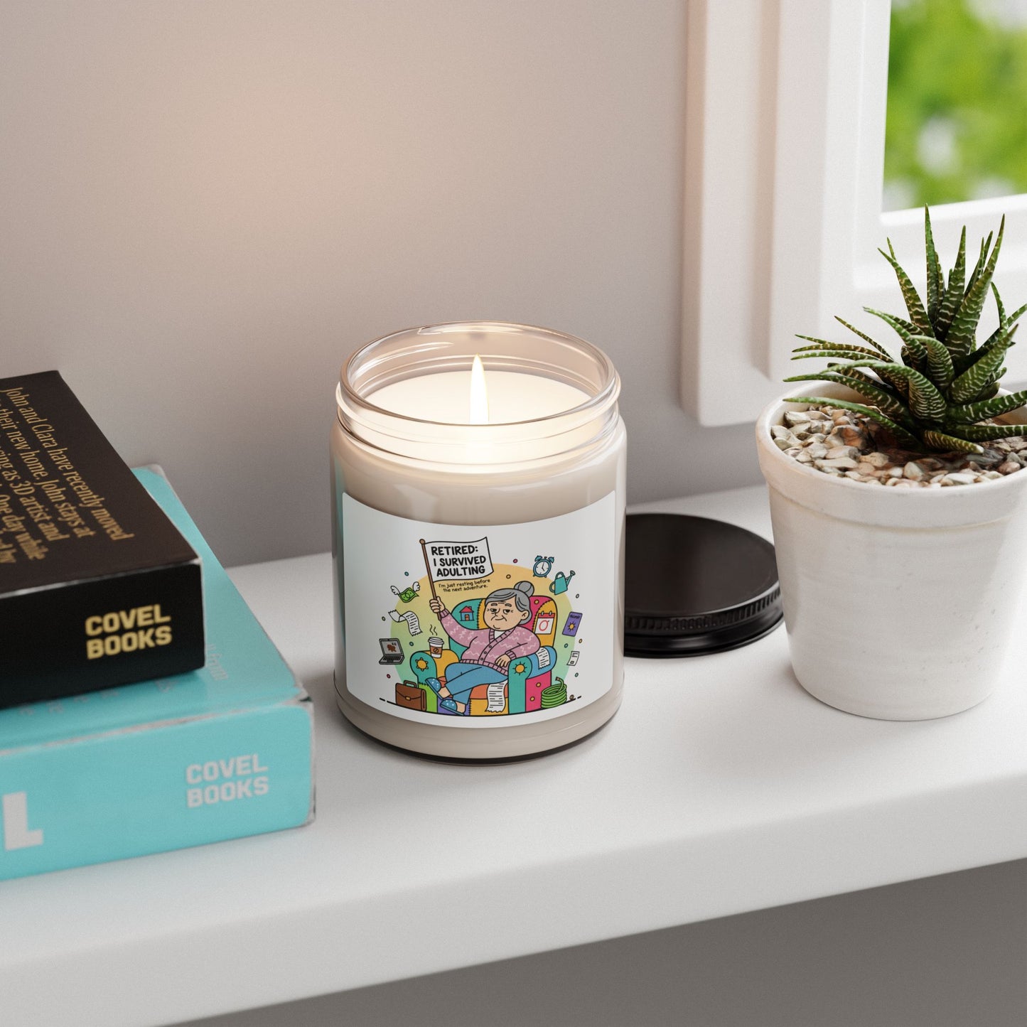 Candle with a colorful label on a shelf next to books and a plant