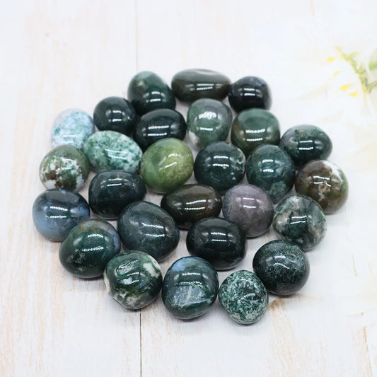 Collection of green and gray marbled stones on a light wooden surface
