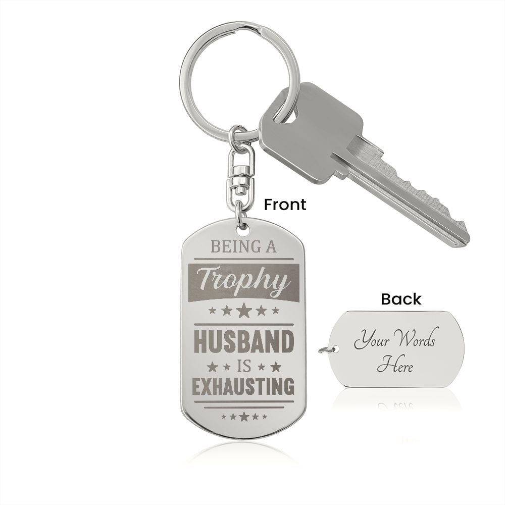 Being a trophy husband is exhausting  Create a unique keepsake with our Engraved Dog Tag Keychain. This high-quality stainless steel piece can be customized on the back in a scripted font, with 2 lines of text, up to 20 characters each.