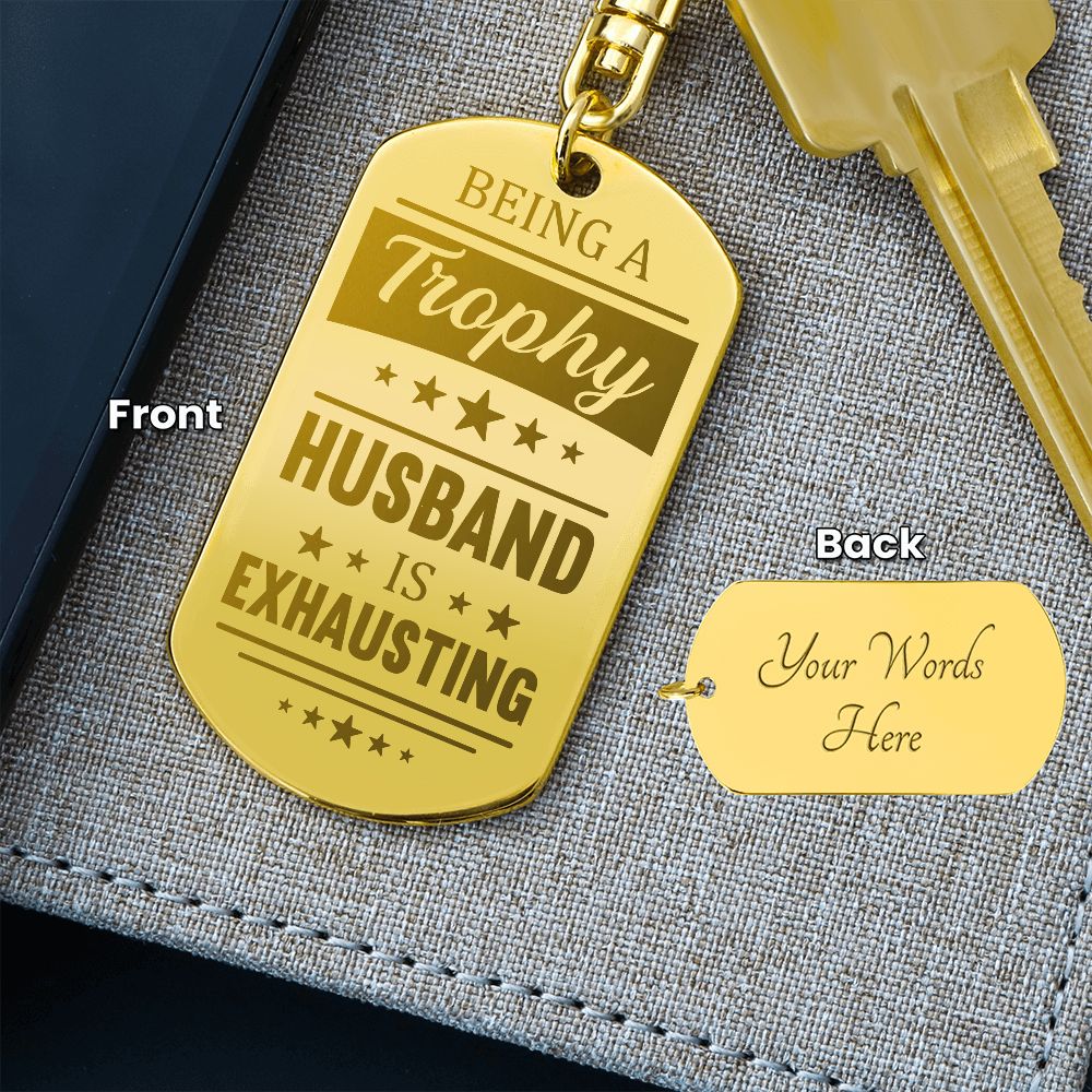 Being a trophy husband is exhausting  Create a unique keepsake with our Engraved Dog Tag Keychain. This high-quality stainless steel piece can be customized on the back in a scripted font, with 2 lines of text, up to 20 characters each.
