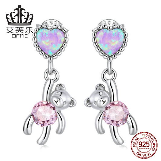 hese earrings feature a unique design: a sterling silver heart shape with opal accents and a small bear engraved into the heart. Crafted from durable sterling silver, the earrings are finished with a bright polished shine and secure latch closure. Show off your style with this one-of-a-kind design and the long-lasting shine of sterling silver.