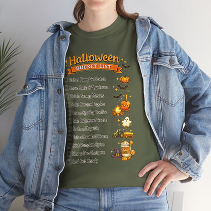 A person wearing an olive green graphic T-shirt with a Halloween bucket list design, layered under a light-wash denim jacket. The graphic features orange pumpkins, bats, a ghost, and a checklist of spooky activities.