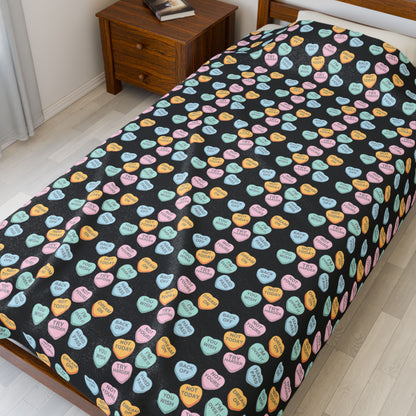 Bed with colorful candy heart patterned bedspread in a bedroom setting.