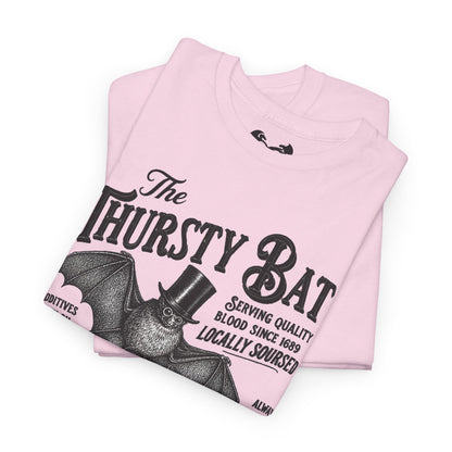 A folded white short-sleeve T-shirt with a large black graphic print reading 'The Thirsty Bat' and a bat illustration wearing a top hat, photographed on a clean white background.
