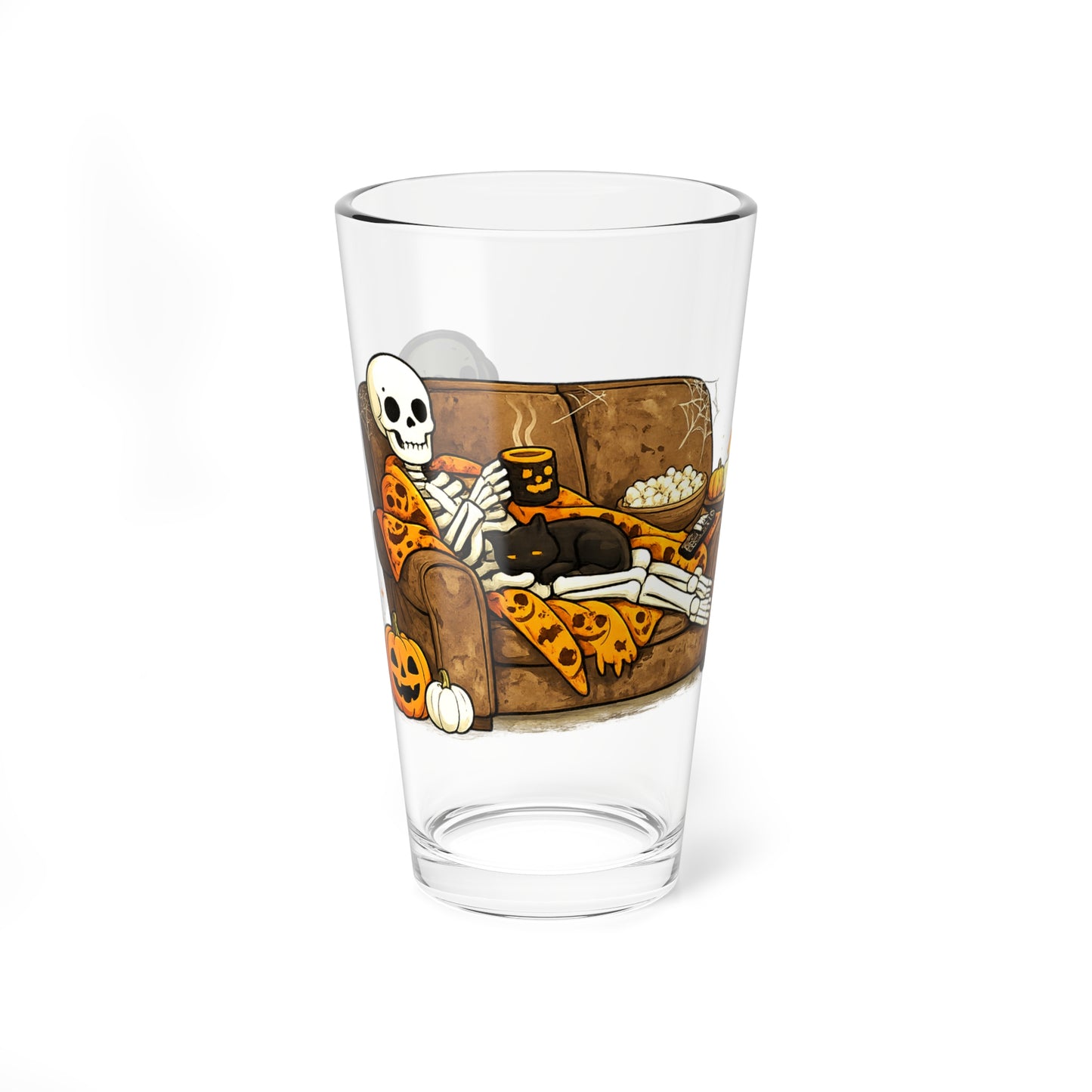 A clear drinking glass featuring a Halloween-themed illustration of a skeleton lounging on a couch with pizza, popcorn, and a black cat, shown on a white background.