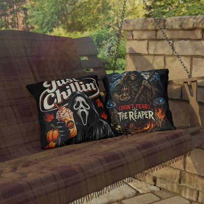 Two Halloween-themed throw pillows displayed on a hanging porch swing with a stone wall and patio in the background. The left pillow features the Ghostface graphic with the text 'Just Chillin'' and a pumpkin drink.