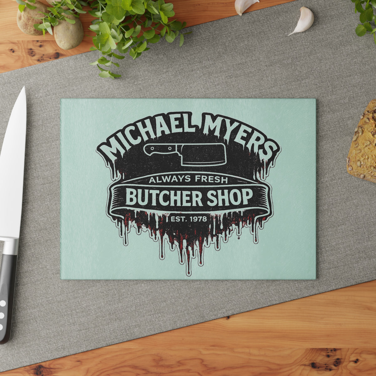 Bring a chilling touch of horror-inspired style to your kitchen with the Michael Myers Butcher Shop Glass Cutting Board. Designed for fans of classic slasher movies and spooky kitchen décor, this bold cutting board combines everyday functionality with a dark, Halloween-inspired aesthetic.