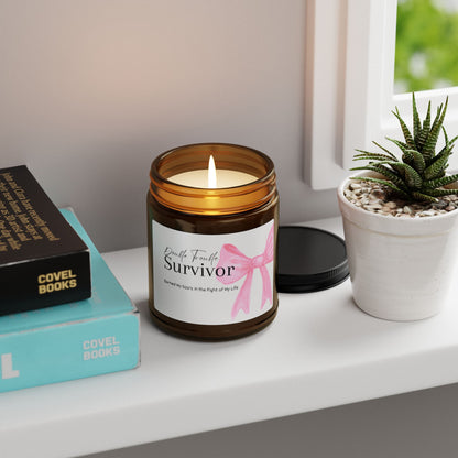 Candle in an amber jar with a 'Survivor' label on a shelf with books and a plant.