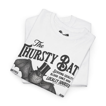 A folded white short-sleeve T-shirt with a large black graphic print reading 'The Thirsty Bat' and a bat illustration wearing a top hat, photographed on a clean white background.