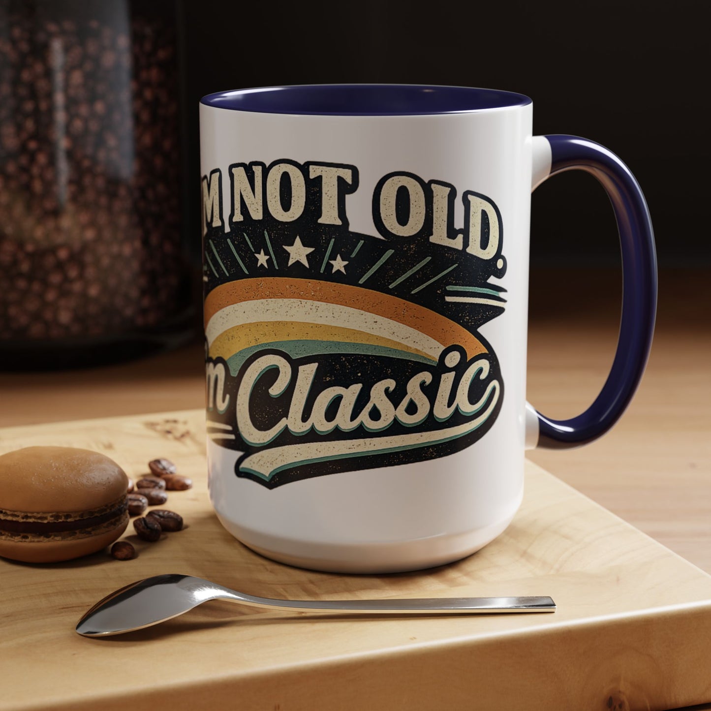 White mug with blue interior and handle, featuring text 'I'm not old, I'm classic', on a wooden surface with coffee beans and a macaron.