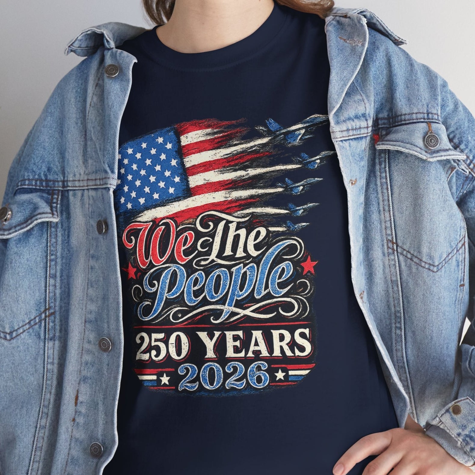 Person wearing a navy blue t-shirt with an American flag design and text, paired with a denim jacket.