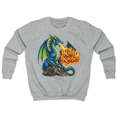 A heather gray crewneck sweatshirt featuring a colorful graphic of a blue and green dragon on a rock, breathing fire toward the text 'King Kooper' in orange flames.