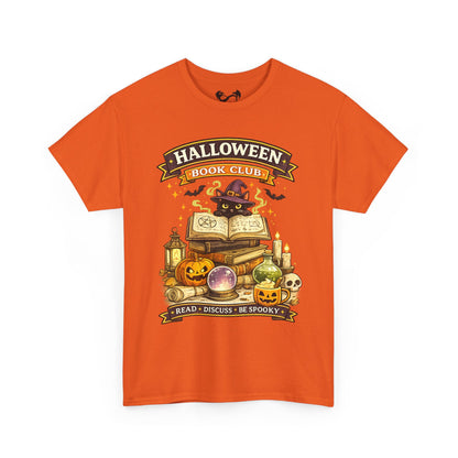 An orange short-sleeve crewneck t-shirt featuring a colorful graphic print on the front with the text 'HALLOWEEN BOOK CLUB' and a spooky illustration of books, pumpkins, a cauldron, and a cat in a witch hat.