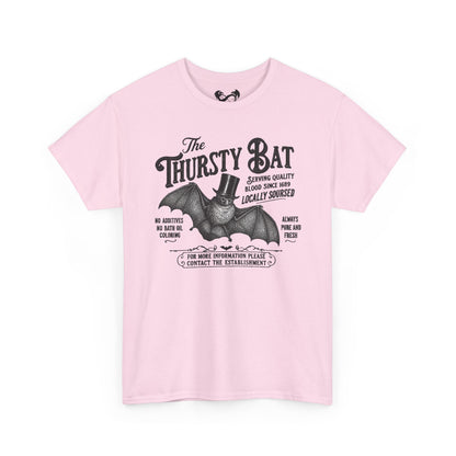 A light pink short-sleeve crewneck t-shirt featuring a vintage-style black graphic of a bat wearing a top hat with the text 'The Thirsty Bat'.