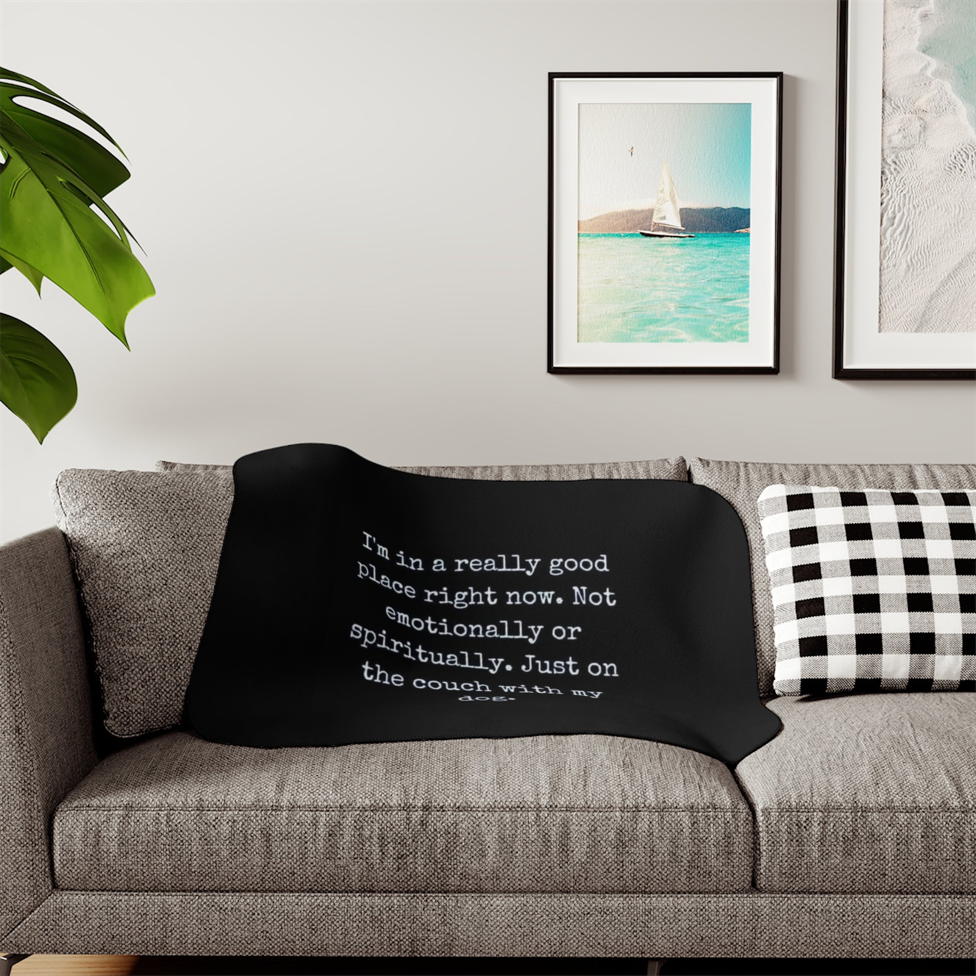 Black blanket with text on a gray couch in a living room setting