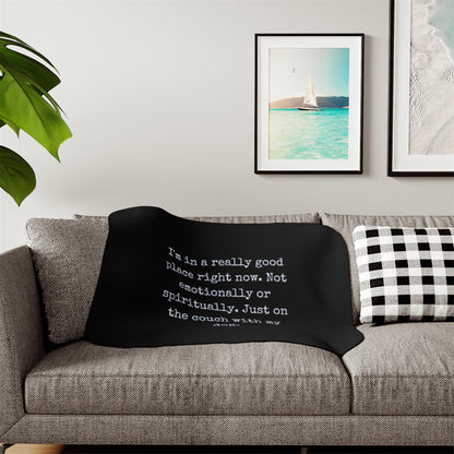 Black blanket with text on a gray couch in a living room setting