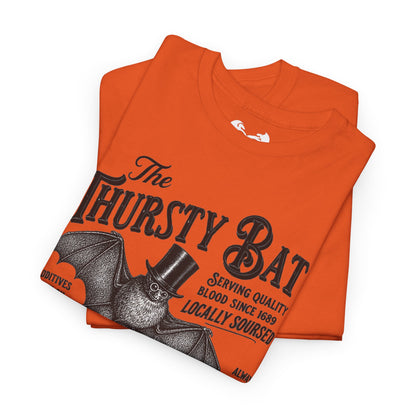 An orange folded t-shirt featuring a vintage-style graphic of a bat wearing a top hat with the text 'The Thirsty Bat' and 'Serving quality blood since 1689'.