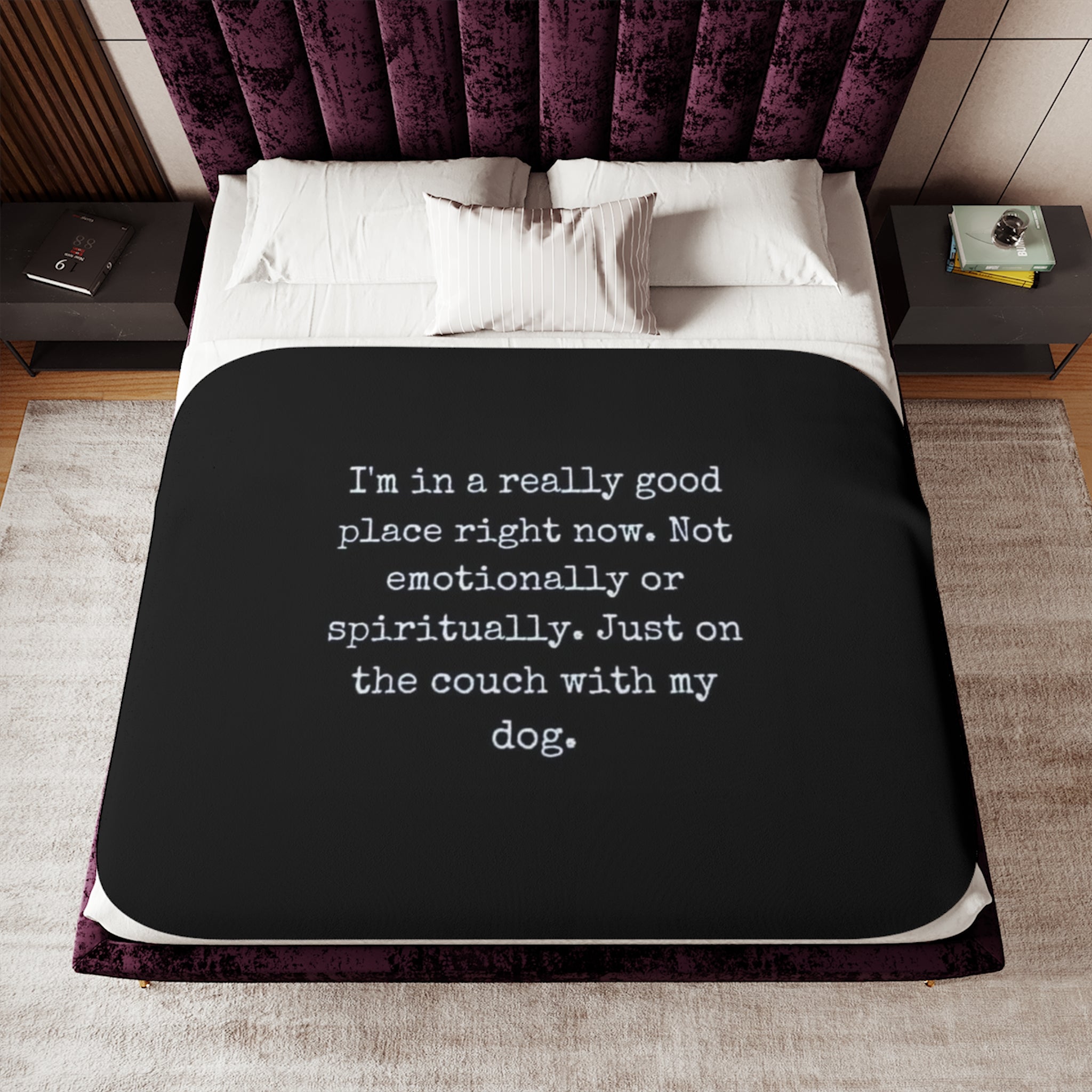 Bed with a black blanket featuring white text and a purple headboard.