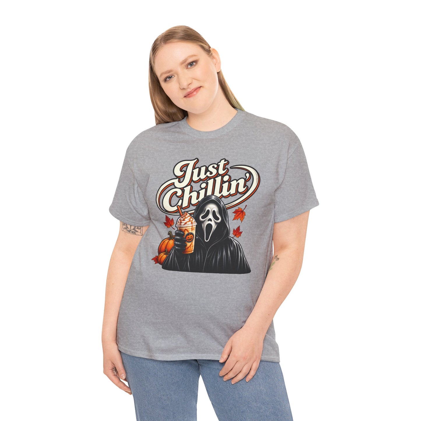 A woman modeling a heather gray graphic t-shirt with a 'Just Chillin'' Ghostface and pumpkin illustration, paired with blue jeans against a plain white background.