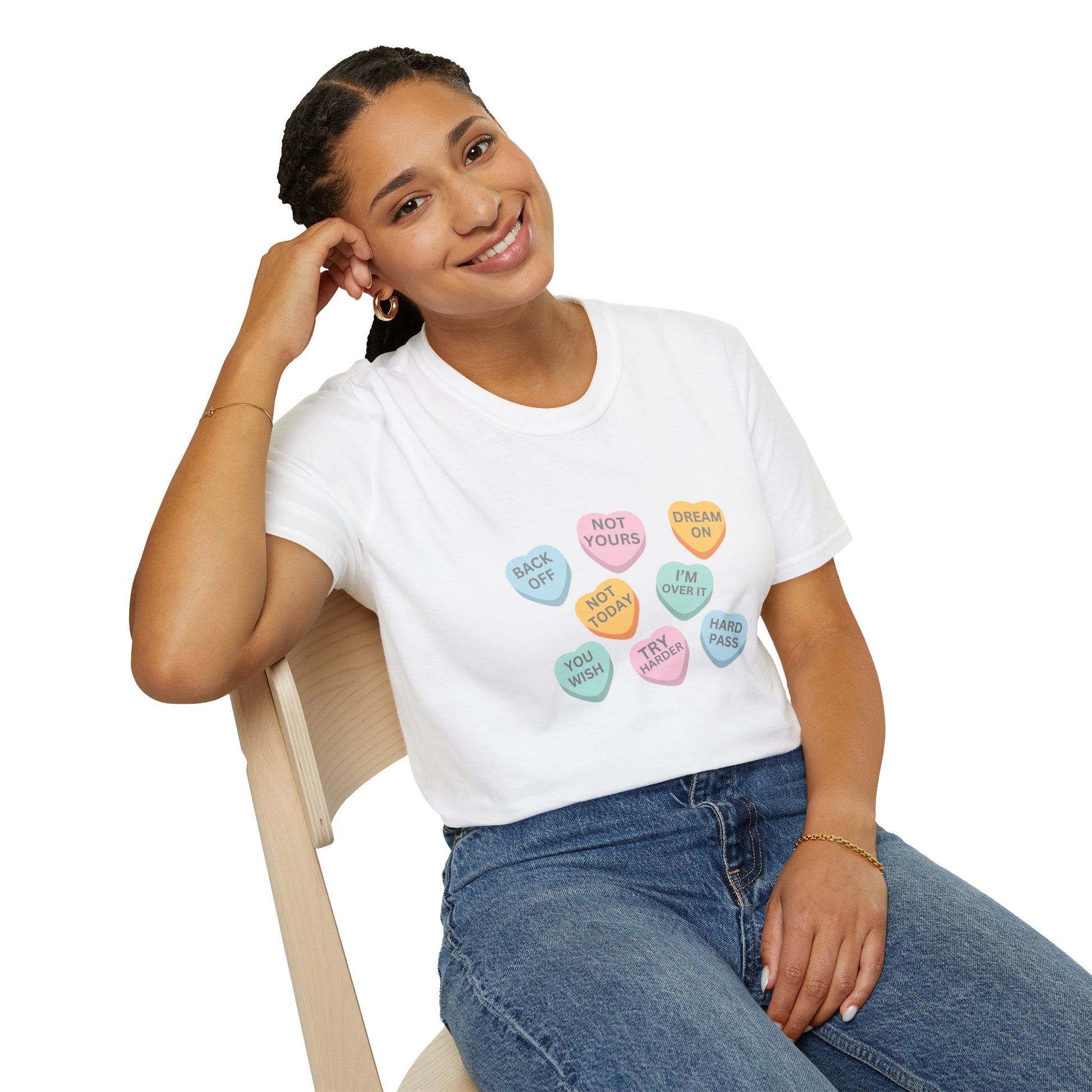Person wearing a white t-shirt with colorful heart-shaped text design, sitting on a chair.