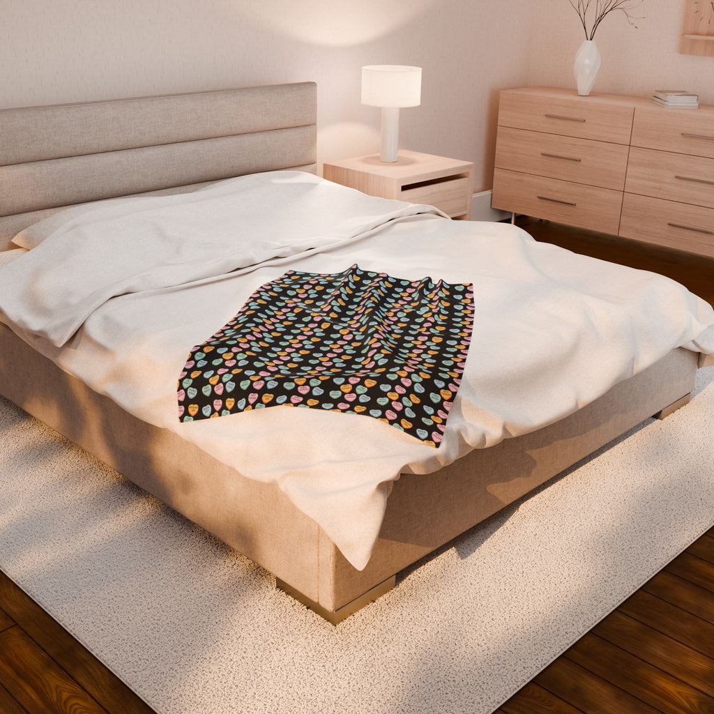 Bedroom with a bed featuring a colorful blanket and wooden furniture.