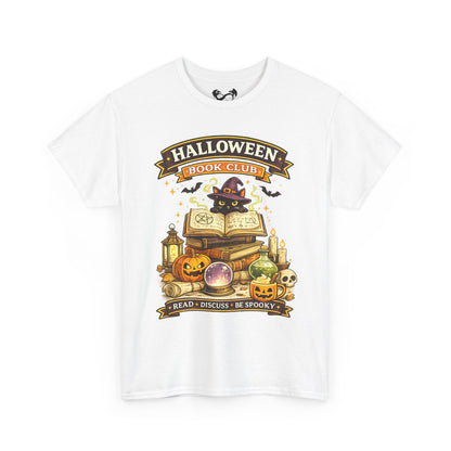 A white short-sleeve crewneck t-shirt featuring a colorful graphic print on the front. The graphic depicts a black cat dressed as a witch sitting on an open book, surrounded by pumpkins, candles, a lantern, and a crystal ball, with banners reading 'HALLOWEEN BOOK CLUB' and 'READ • DISCUSS • BE SPOOKY'.