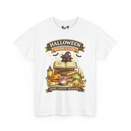 A white short-sleeve crewneck t-shirt featuring a colorful graphic print on the front. The graphic depicts a black cat dressed as a witch sitting on an open book, surrounded by pumpkins, candles, a lantern, and a crystal ball, with banners reading 'HALLOWEEN BOOK CLUB' and 'READ • DISCUSS • BE SPOOKY'.
