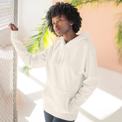 Person wearing a white hoodie standing against a light background with plants.