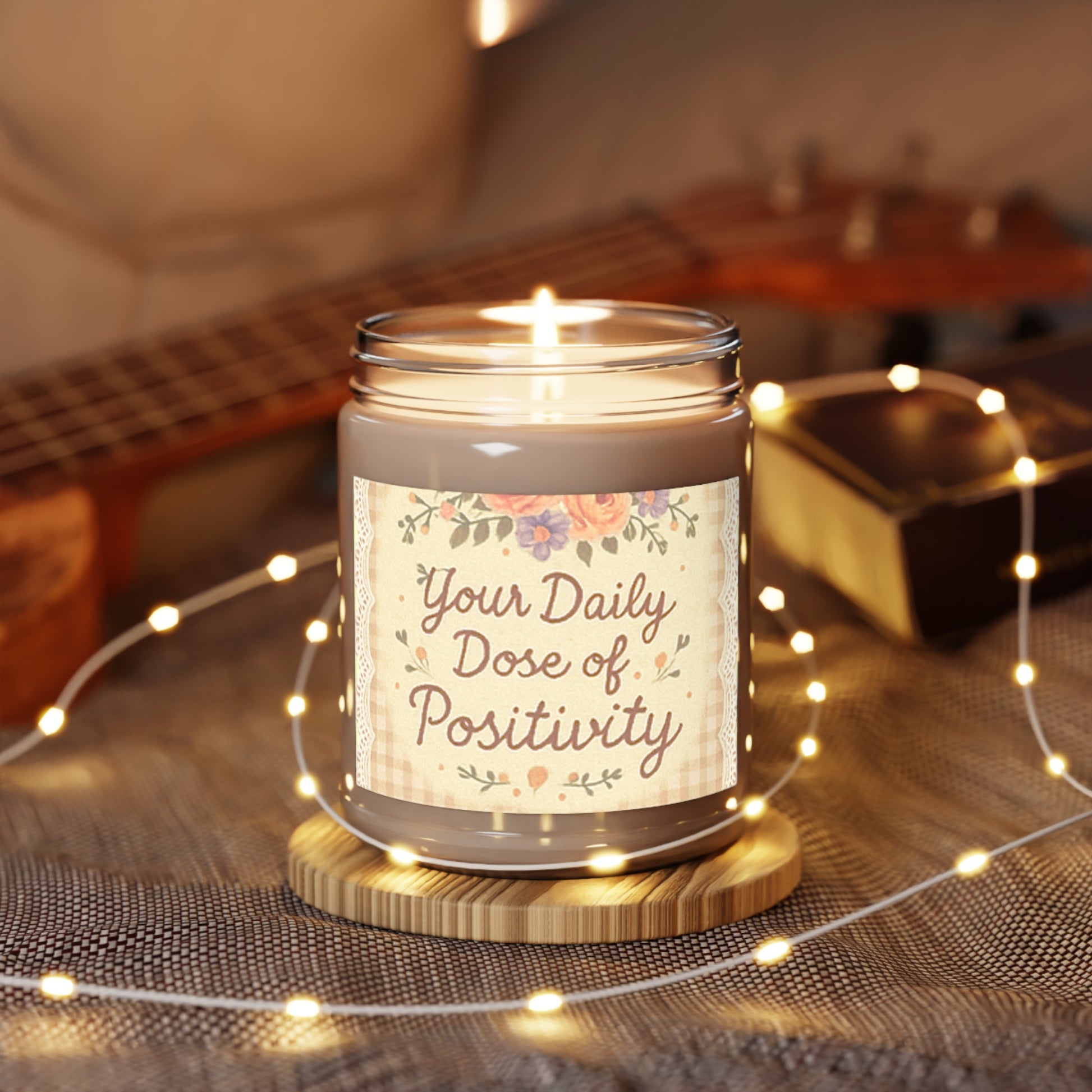 Candle in a jar with 'Your Daily Dose of Positivity' text, surrounded by string lights and a guitar in the background.