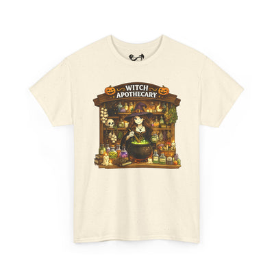 An off-white short-sleeve crewneck t-shirt featuring a colorful graphic print of a whimsical witch apothecary shop with a cauldron, potions, and pumpkins.