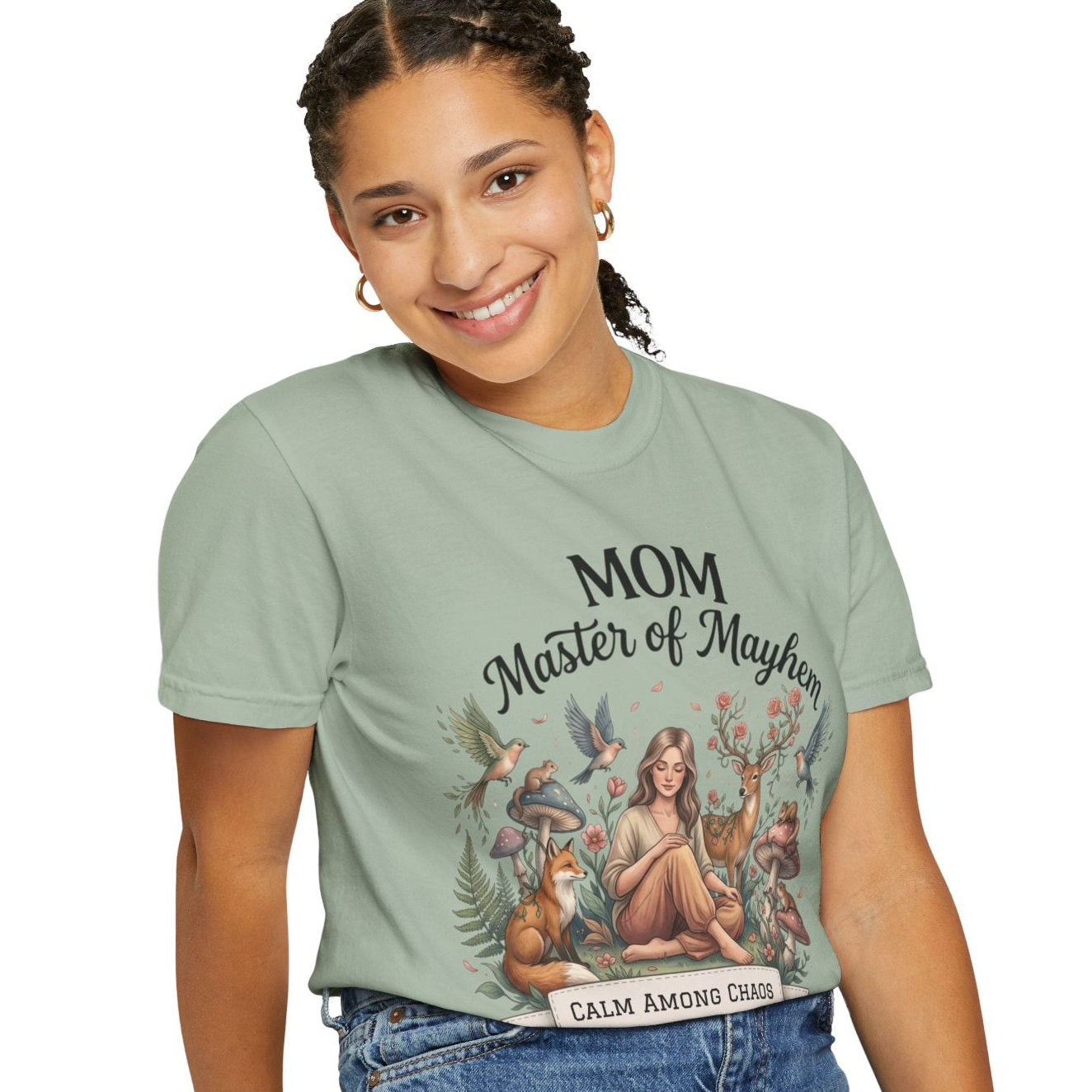 Woman wearing a green t-shirt with a graphic design and text, sitting on a stool against a white background.