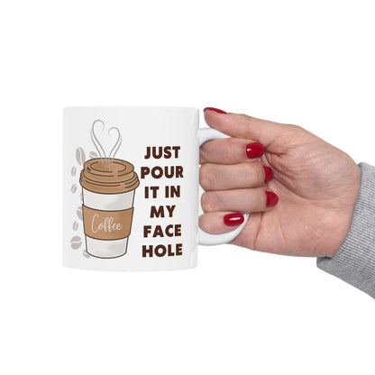 Mug with coffee graphic and text held by a hand on a white background