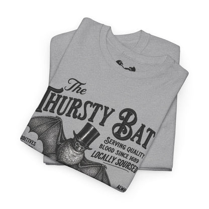 A folded light gray heather t-shirt featuring a vintage-style black graphic of a bat wearing a top hat with the text 'The Thirsty Bat' and 'Serving quality blood since 1689'.