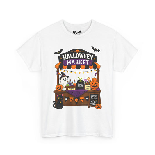 A white short-sleeve crewneck t-shirt featuring a colorful graphic print of a 'Halloween Market' stall with pumpkins, ghosts, bats, and witches on a clean white background.