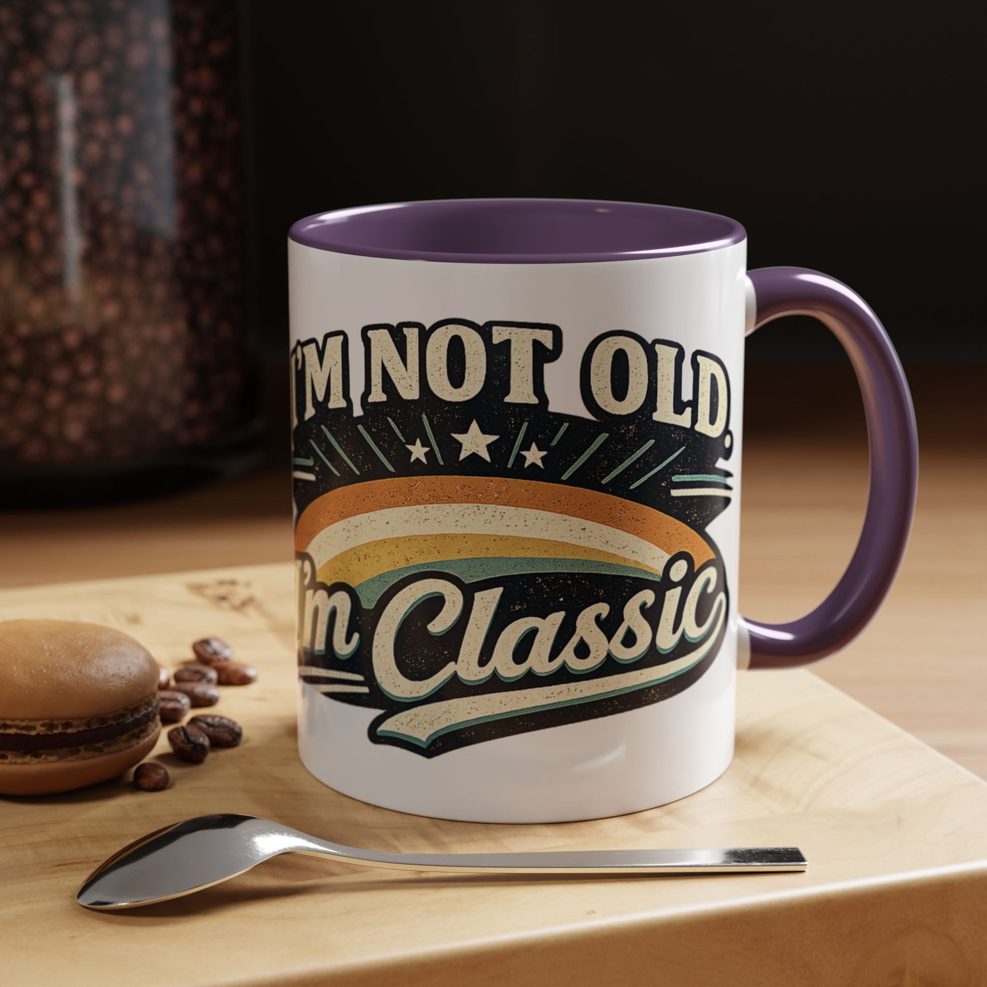 Mug with 'I'm not old, I'm classic' text on a wooden surface with coffee beans and a spoon.
