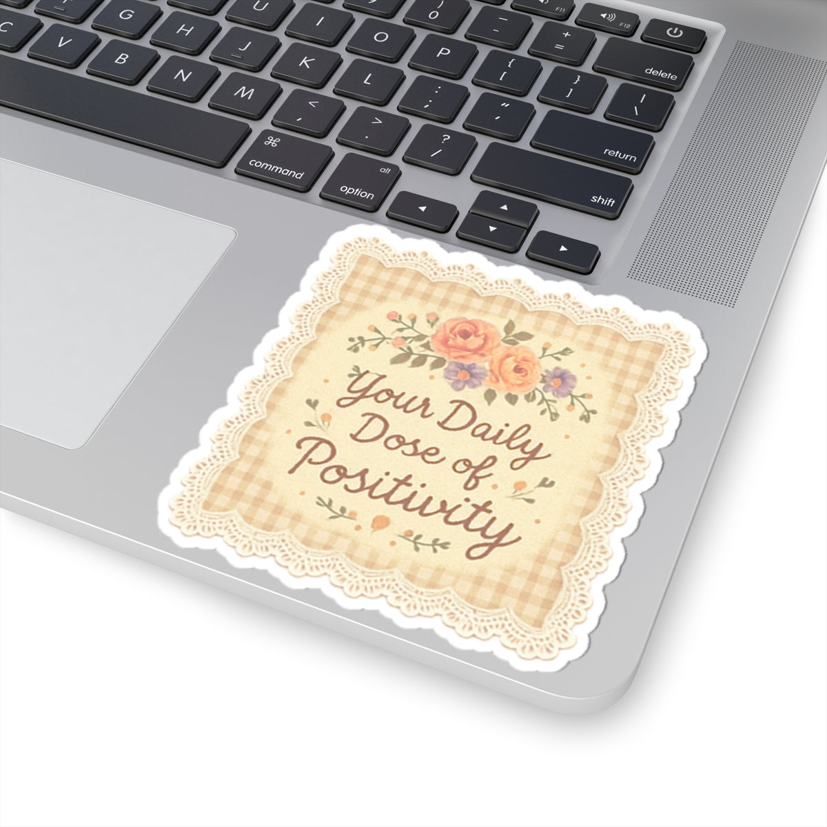 Decorative sticker with 'Your Daily Dose of Positivity' text on a laptop keyboard