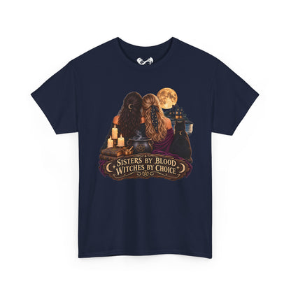 A navy blue short-sleeve t-shirt with a graphic print on the front depicting two witches with long hair, cauldrons, candles, and a full moon, with the text 'SISTERS BY BLOOD WITCHES BY CHOICE'.