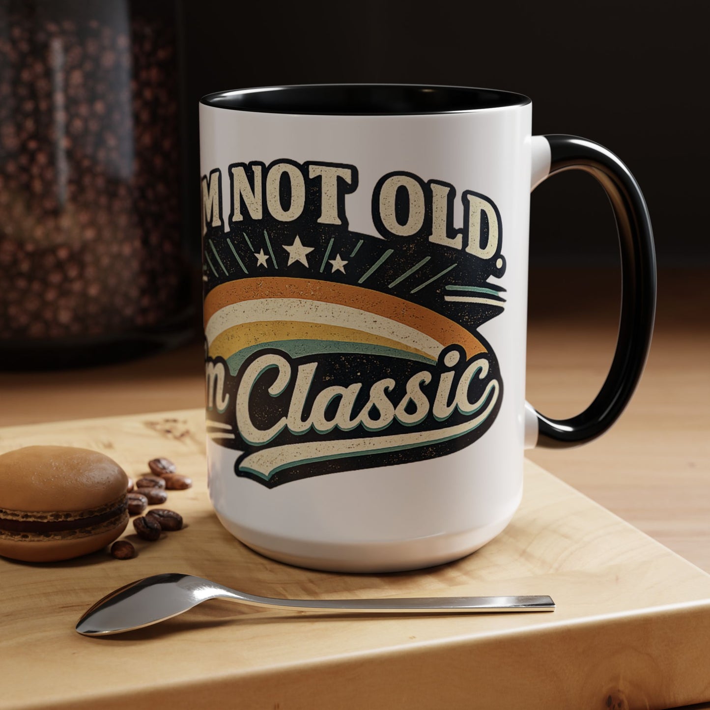 White mug with black interior and handle, featuring text 'I'm not old, I'm classic', on a wooden surface with coffee beans and a cookie.