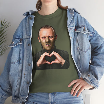 A person wearing an olive green graphic t-shirt with a print of a man in a mask making a heart shape with his hands, styled with an open light-wash denim jacket.