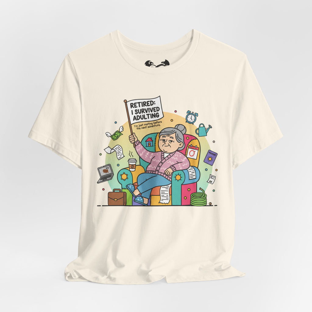 Beige t-shirt with a colorful graphic of a retired person holding a sign 'Retired: I survived adulting' on a light gray background.