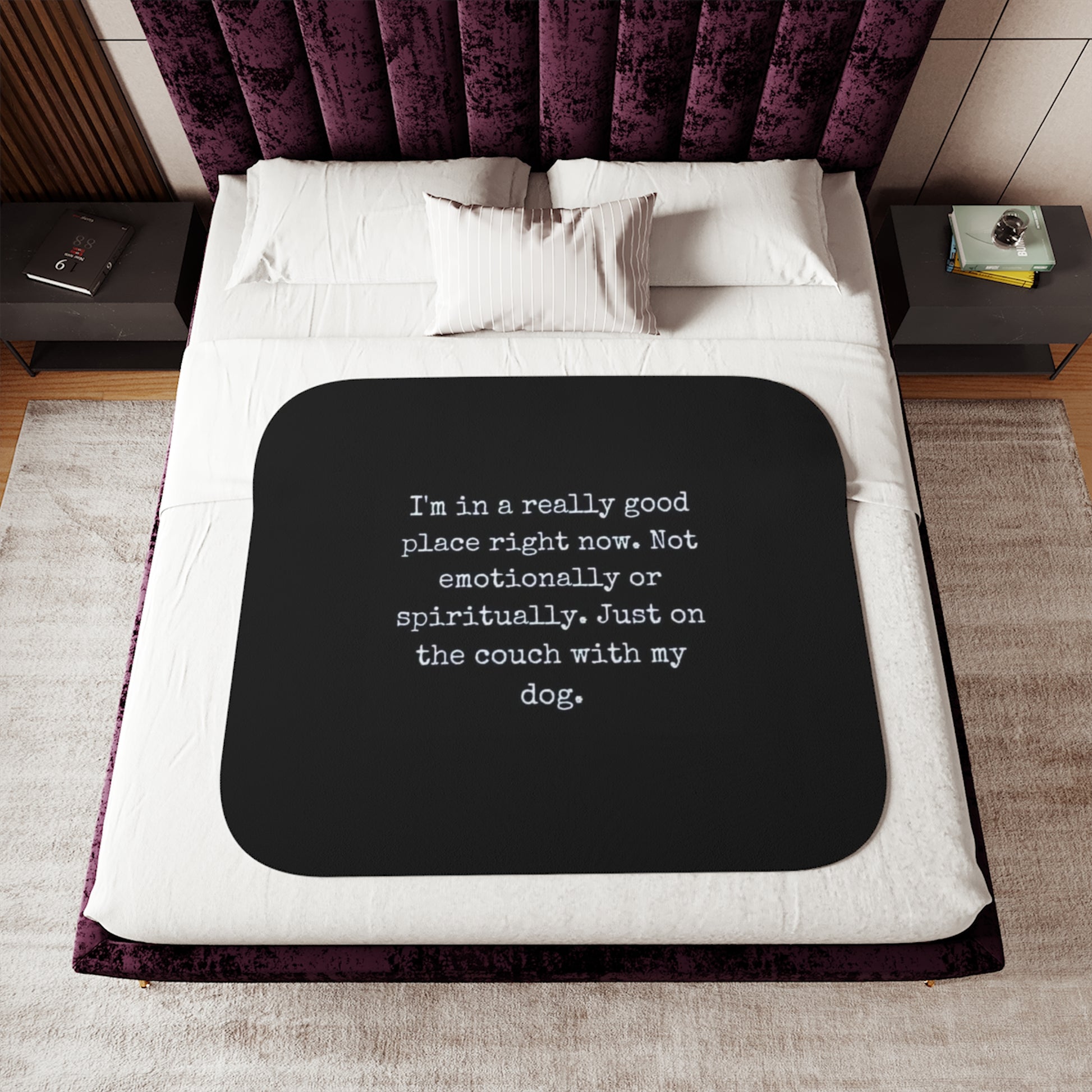 Bed with a black mat featuring text on a white bedspread, purple headboard, and wooden nightstands.