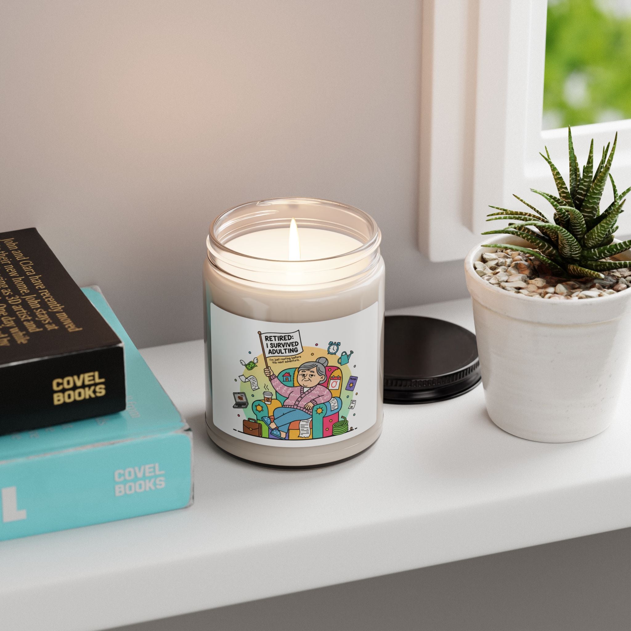 Candle with a colorful label on a shelf next to books and a plant