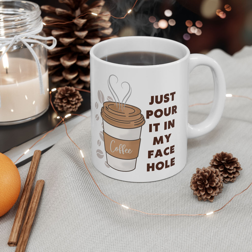 White mug with coffee-themed design and text, surrounded by decorative items on a table.